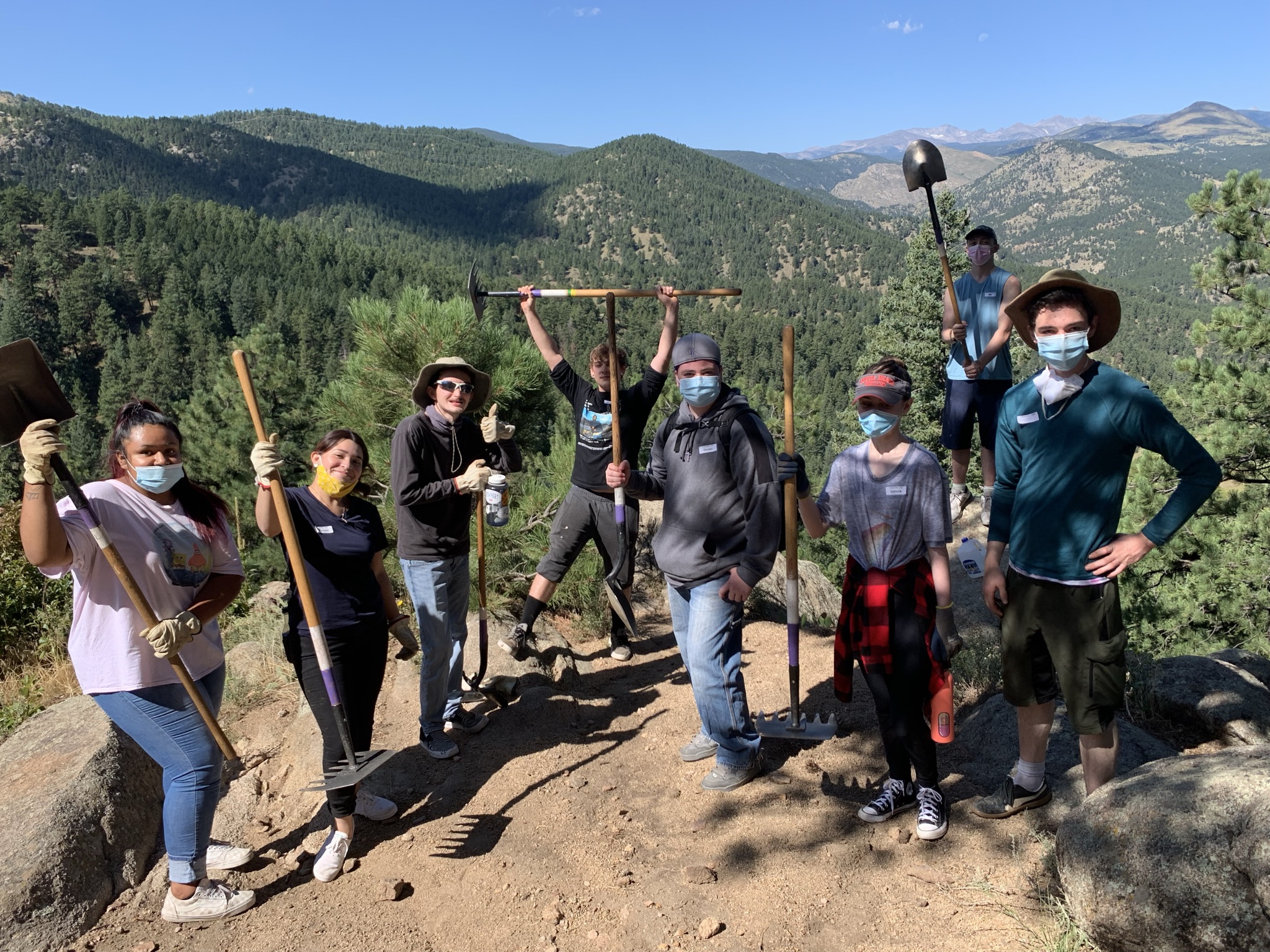 Group of students holding shovels in the mountains.