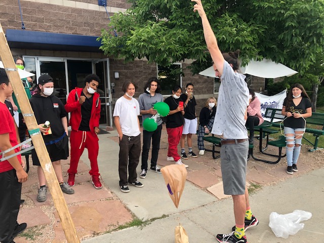 Teacher dropping a protected egg for egg drop in front of a group of students.