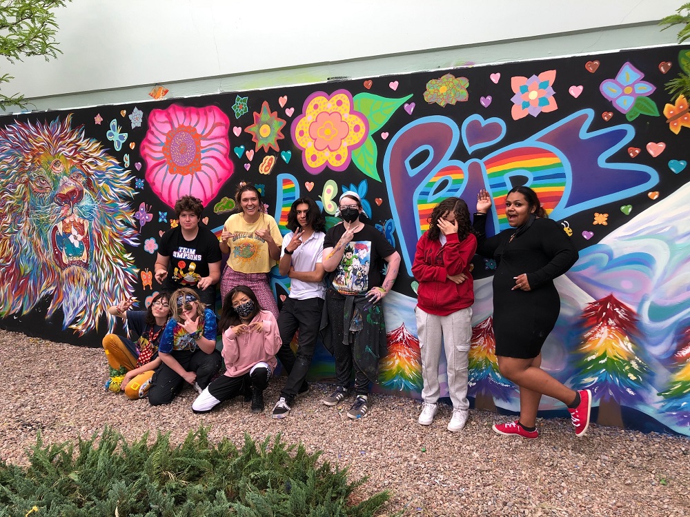 Mural art class standing in front of mural wall art.